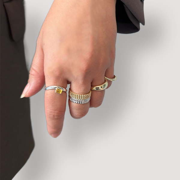 Hand wearing multiple rings on a plain background