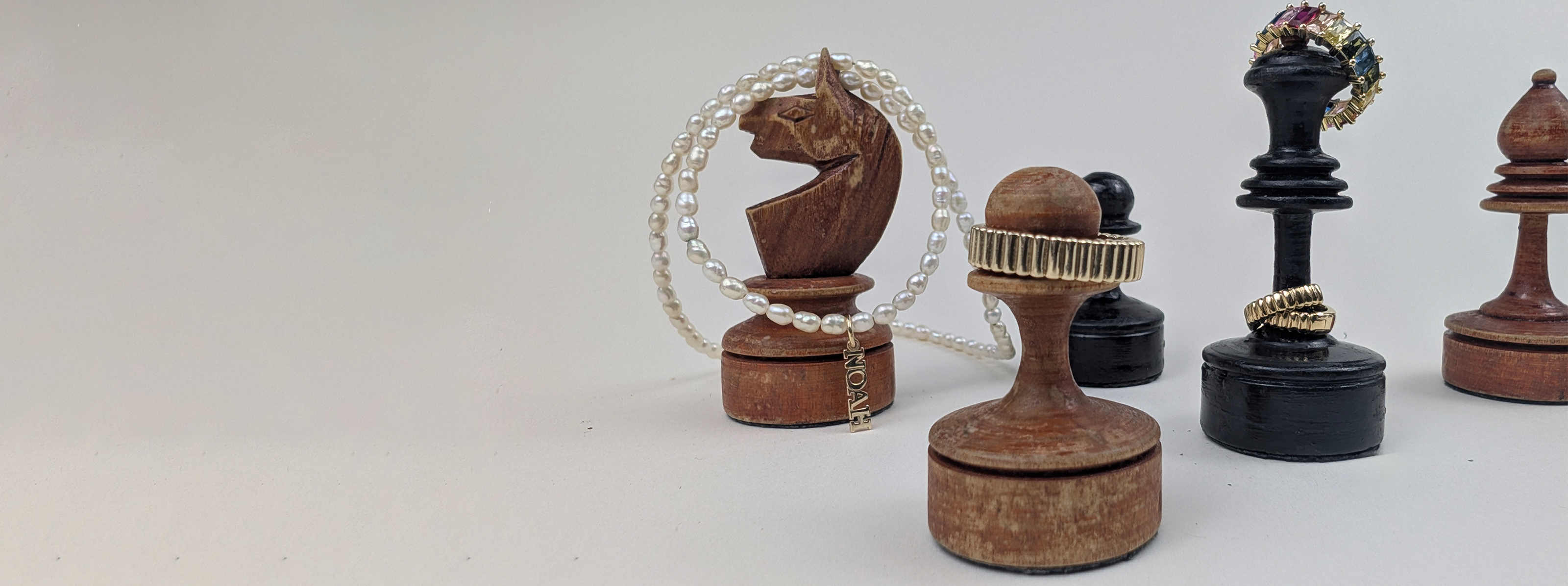 Wooden chess pieces with jewelry on them on a light gray background
